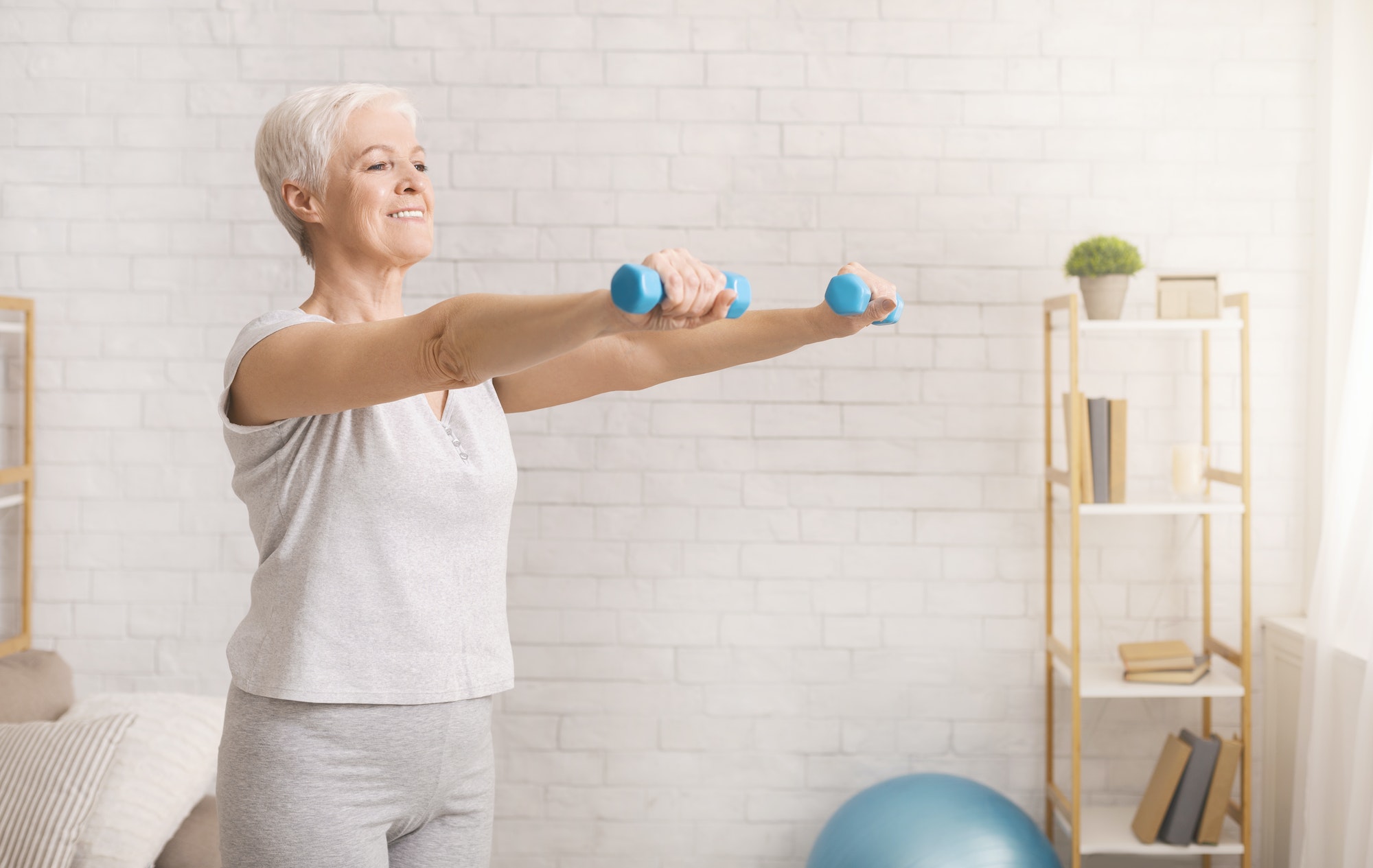 Senior woman exercising with dumbbells at home